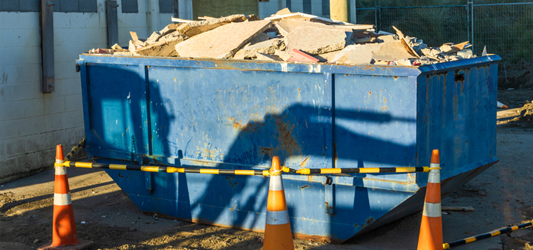 Blue construction dumpster full of concrete 