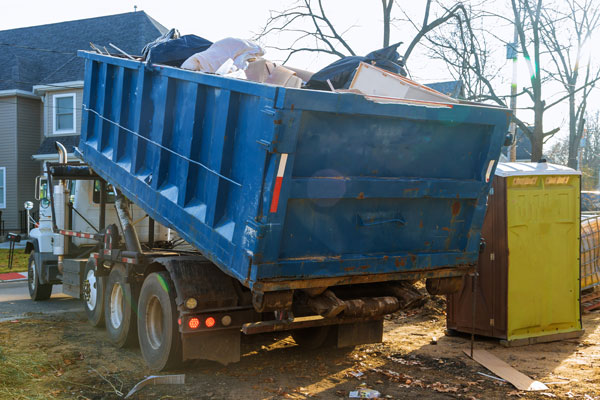 Roll-off dumpster full of waste being loaded onto dumpster truck