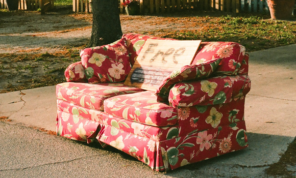 couch sitting on curb with a free sign attached to it
