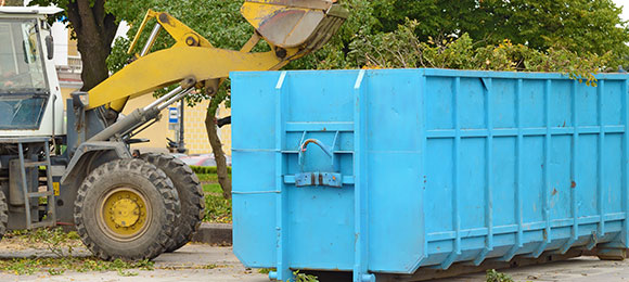 excavator placing yard waste in 30 yard dumpster