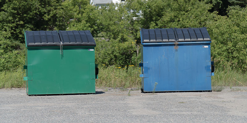 commercial waste and recycling dumpsters in parking lot