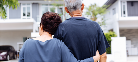 older couple embracing and facing a home