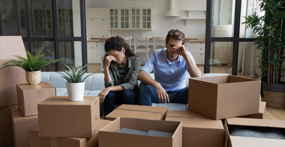 Distressed couple surrounded by moving boxes
