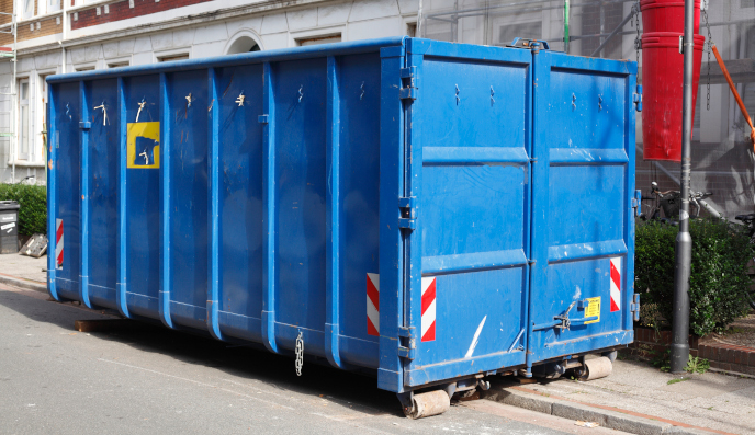 Blue dumpster on the side of a public roadway