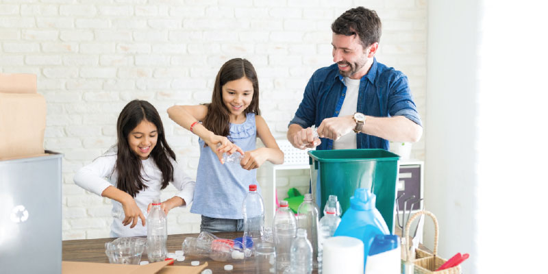 Father and daughters sorting through plastic to place into recycling bin