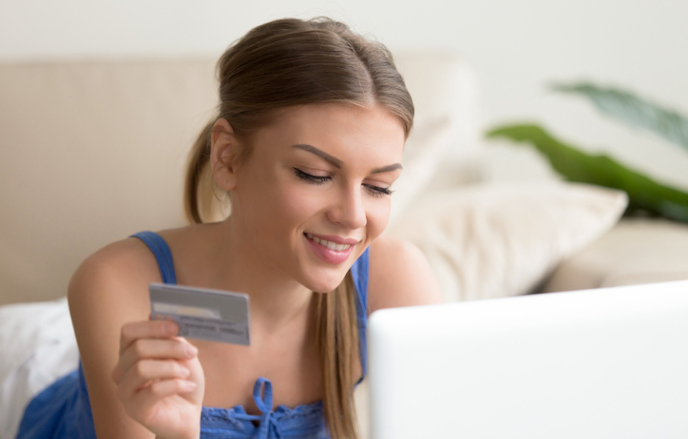 woman holding her credit card and looking at computer