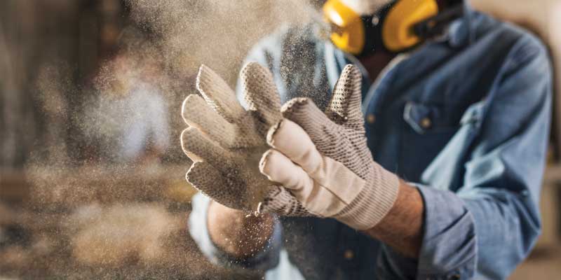 Man shaking construction dust off work gloves