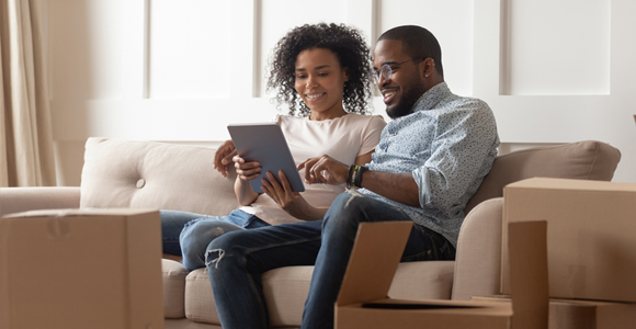 Couple looking at tablet in room full of moving boxes