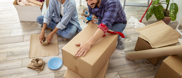 Couple packing up kitchen items into moving boxes