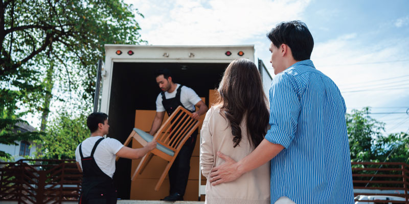couple watching professionals load their dining room set onto truck