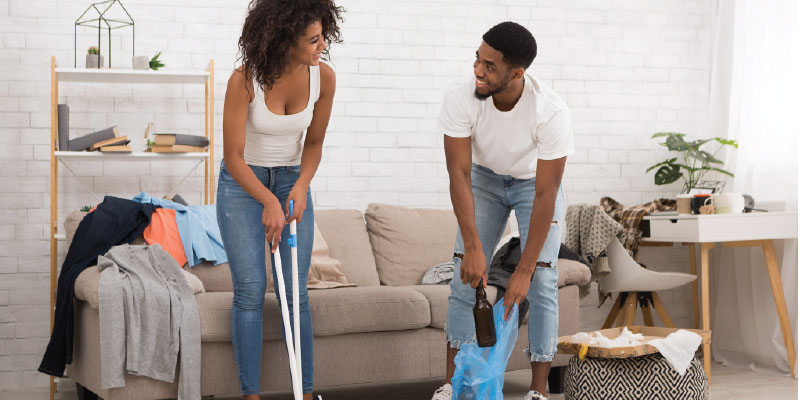 Couple cleaning up messy living room