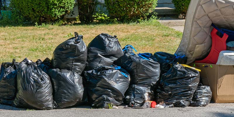 garbage bags and other household junk sitting at curb for pick-up