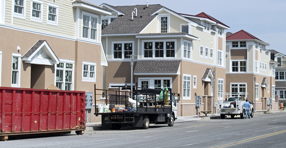 Roll-off trash dumpster and trailer dumpster in street next to apartments