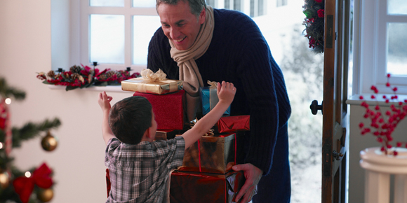 kid running toward dad holding Christmas gifts