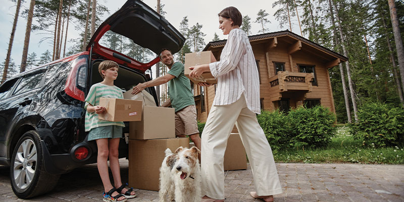 family unpacking moving boxes from car