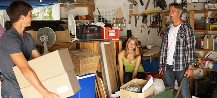 Family helping each other move boxes out of full garage