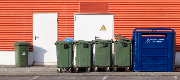 2 yard dumpster next to small roller trash carts