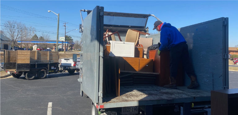 junk removal crew loading hauling vehicle with old furniture