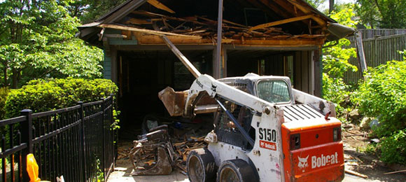 excavator tearing down small garage