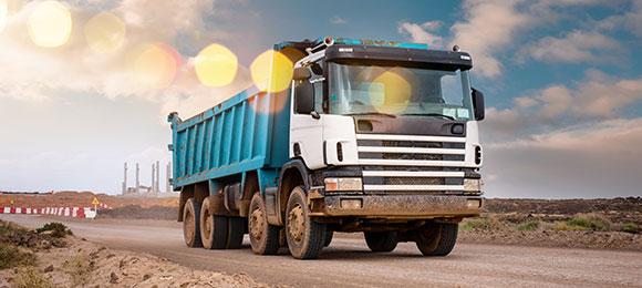 roll-off dumpster truck driving away from landfill