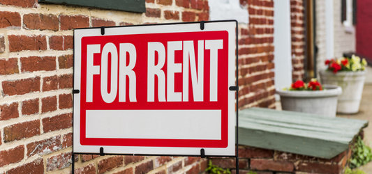 a "for rent" sign in front of an apartment building