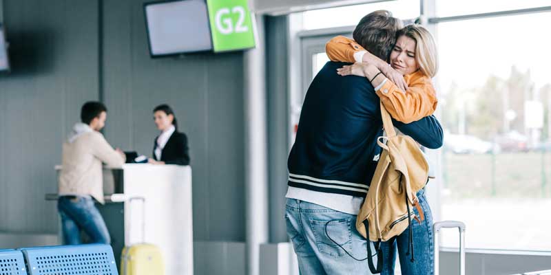 Woman in tears hugging loved one at airport
