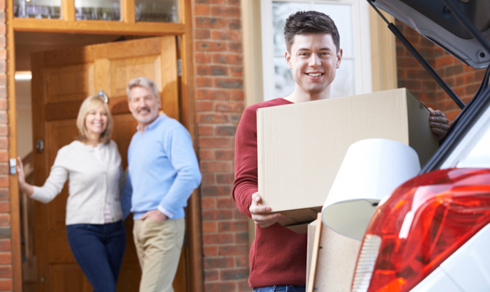 grown child moving boxes out of parents' home as they look on