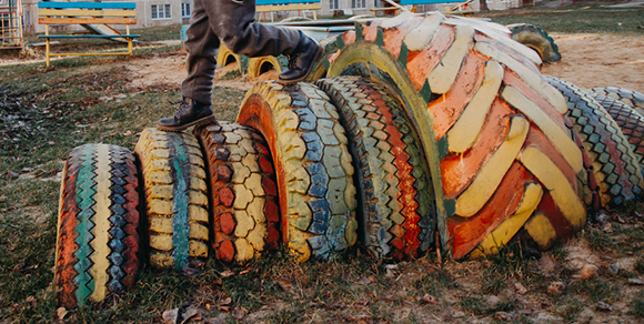 Child playing on playground with painted, repurposed rubber tires as part of the structure