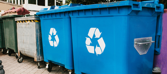 Blue commercial recycling dumpsters next to regular trash commercial dumpsters