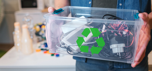 Person holding small clear recycling bin full of electronics