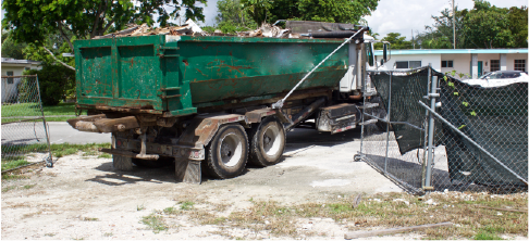 truck driving large dumpster off of residential work site