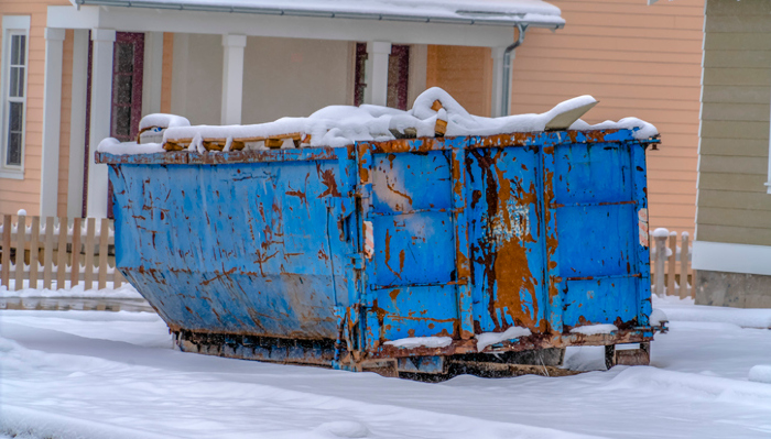 Roll-off dumpster surrounded by and covered in snow