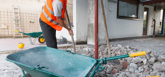 Junk removal pro loading concrete debris into wheelbarrow