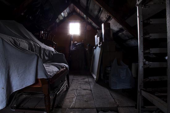 poorly lit attic full of boxes and old furniture