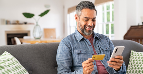 smiling man making credit card payment on his smart phone