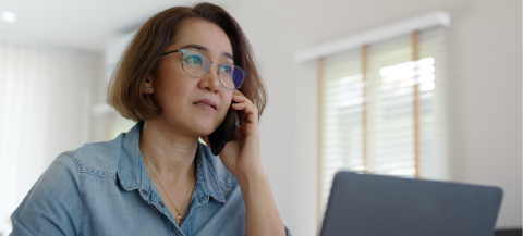 woman looking at computer while on the phone