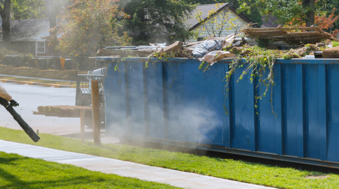 A full blue roll-off dumpster on the side of a street