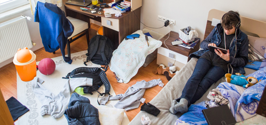 teen sitting in messy bedroom