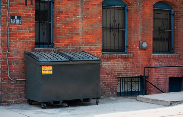 Commercial dumpster against brick building