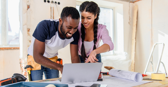 man and woman looking at laptop in a room being renovated