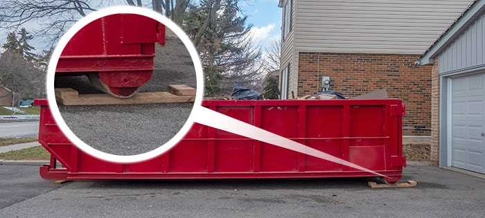 plyboards placed under a roll-off dumpster to protect driveway