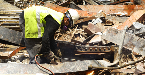 Man sorting through construction and demolition debris dressed in personal protective equipment