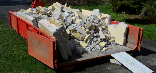 lowboy roll-off dumpster full of concrete debris