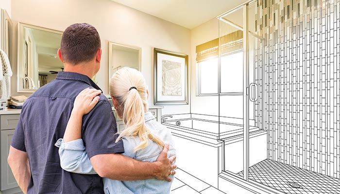 couple proudly looking at bathroom remodel blueprint