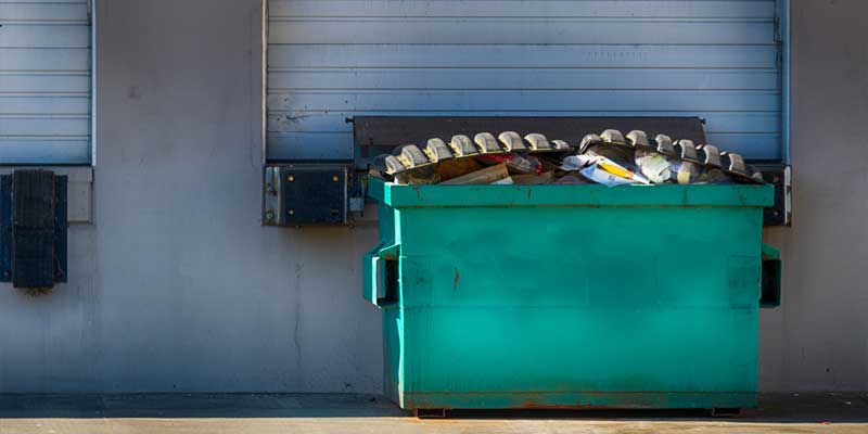 Green commercial dumpster full of garbage