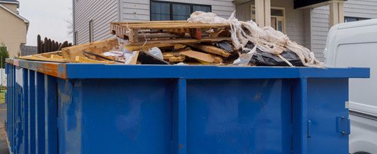 dumpster full of debris in front of house