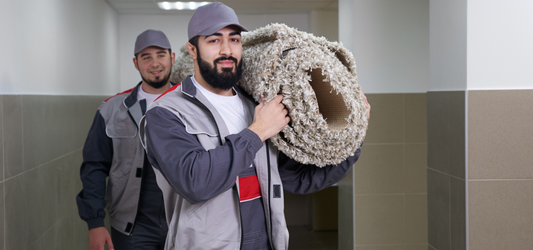 Two junk removal pros removing heavy rolled up carpet