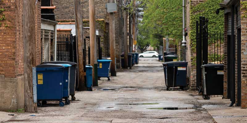 Commercial dumpsters outside of businesses in an alleyway