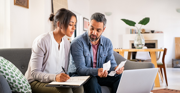 couple sitting on couch calculating their budget