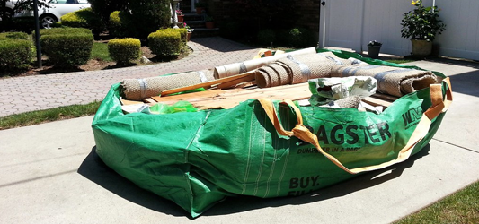 Bagster on residential driveway overflowing with wood and carpet